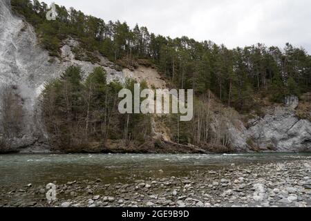 Riva rocciosa del fiume Reno anteriore in Ruinaulta orrido o gola in Svizzera. Sullo sfondo si trova una parete rocciosa ricoperta di conifere. Foto Stock