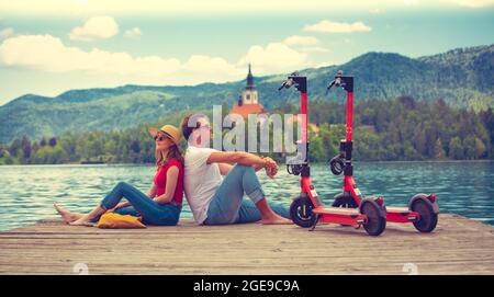 Giovane coppia che usa lo scooter elettrico come moderno mezzo di trasporto ecologico mentre esplora il verde paese Slovenia in vacanza. Energia ecologica verde Foto Stock