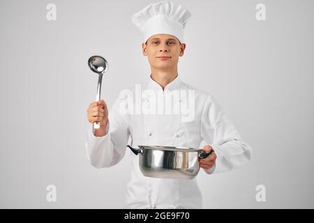 un uomo che tiene una pentola cucinando con un professionista Foto Stock