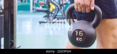 Uomo che tiene il kettlebell in palestra Foto Stock