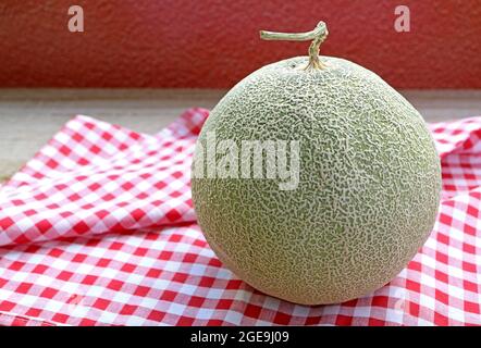 Muskmelon fresco maturo o melone Cantaloupe con gambo isolato su dama panno da cucina Foto Stock