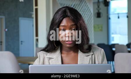 Donna afroamericana parla di videochat via laptop in caffetteria Foto Stock