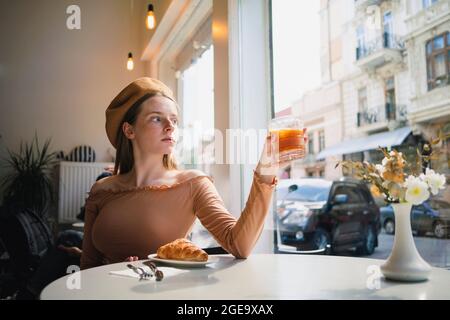 Femmina a piena lunghezza in giobilo con pattina rosa sui rulli per scattare foto istantanee su un terreno sportivo soleggiato Foto Stock