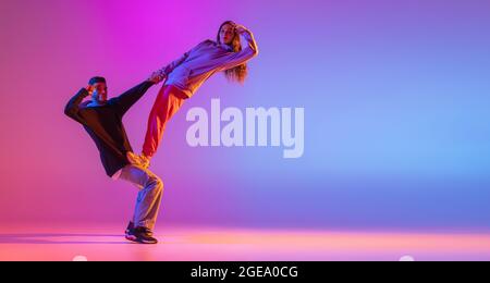 Volantino. Due giovani, un ragazzo e una ragazza che ballano la danza contemporanea, hip-hop su sfondo rosa con luce al neon. Foto Stock