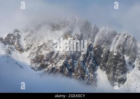 Cima di montagna coperta di neve avvolta dalla nebbia. Foto Stock