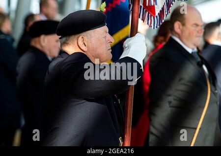 Un portatore di bandiera di un Veterano militare è all'attenzione della domenica della memoria che porta la bandiera dell'Unione. Foto Stock