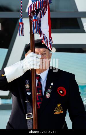 Un portatore di bandiera di un Veterano militare è all'attenzione della domenica della memoria che porta la bandiera dell'Unione. Foto Stock