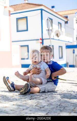 Fratello maggiore che tiene un piccolo mentre gioca all'aperto Foto Stock