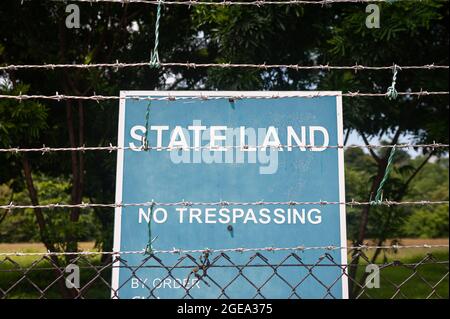 30.07.2020, Singapore, Repubblica di Singapore, Asia - un segno di divieto con l'iscrizione 'Stato Terra No Trespassing' su una proprietà dietro un barbato Foto Stock