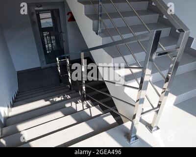 Scale moderne con ringhiera in metallo nell'edificio degli uffici. Scala con piastrelle grigie. Uscita di emergenza nel centro commerciale o d'affari. Foto Stock