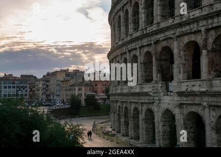 Un paio di passeggiate sotto l'imponente struttura del Colosseo di Roma. Foto Stock