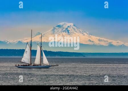 Avventurosa goletta in barca a vela sulla baia di Elliot di Puget Sound vicino a Seattle, con il Monte Rainier che torreggia sullo sfondo, Washington state, USA [editoriale