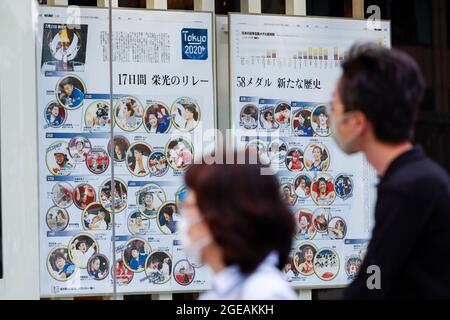 Tokyo, Giappone. 18 agosto 2021. I pedoni che indossano maschere facciali camminano davanti a un poster che mostra i medalisti olimpici giapponesi a Tokyo 2020 nell'area dello shopping di Ginza. Mercoledì il governo metropolitano di Tokyo ha confermato 5,386 nuovi casi di infezione da coronavirus nella capitale. (Credit Image: © Rodrigo Reyes Marin/ZUMA Press Wire) Credit: ZUMA Press, Inc./Alamy Live News Foto Stock