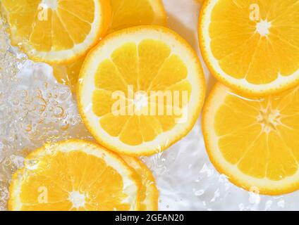 Primo piano di arance in liquido con bolle. Fette di arance succose in acqua. Primo piano fette fresche di arance su sfondo bianco Foto Stock