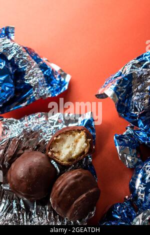 Alcuni cioccolatini e alcuni diversi involucri colorati sulla superficie arancione Foto Stock