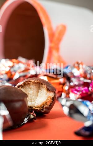 Alcuni cioccolatini e alcuni diversi involucri colorati sulla superficie arancione Foto Stock