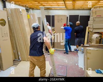 Londra. UK- 08.13.2021: Lavoratori che trasportano pacchi pesanti in un magazzino. Foto Stock