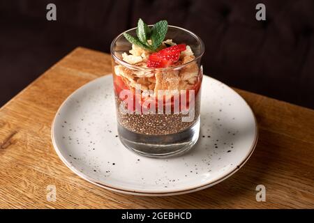 dieta colazione sana. seme chia, fragole e muesli in un bicchiere, fragola fresca su sfondo di legno Foto Stock