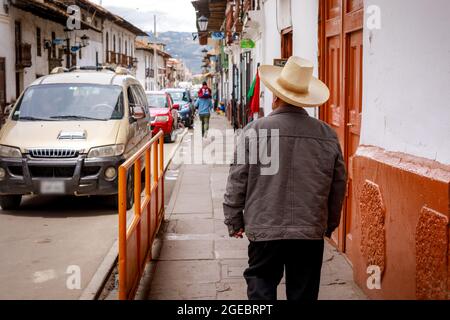 Un uomo peruviano che indossa un cappello tradizionale che cammina lungo la strada nel centro della città di Cajamarca in Perù Foto Stock