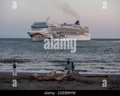 Gente locale sulla spiaggia guardando la nave da crociera Norwegian Jewel lasciando Puntarenas, Costa Rica. Foto Stock