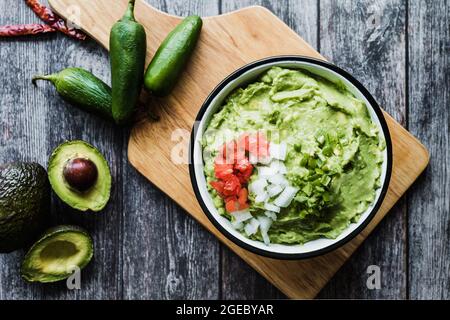 Ciotola di Guacamole accanto a ingredienti freschi su un tavolo di legno in Messico Foto Stock