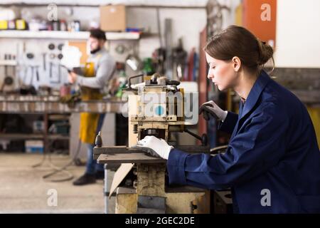 Craftswoman che lavora su una macchina per la perforazione di strutture metalliche Foto Stock