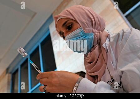 Un operatore sanitario arabo israeliano prepara una dose del vaccino Pfizer-BioNtech COVID-19 presso il centro di vaccinazione notturno aperto nel complesso del municipio il 17 agosto 2021 a Gerusalemme, Israele. Più di un milione di israeliani hanno ricevuto il colpo di richiamo della terza dose mentre il governo corre a squelch la diffusione della variante Delta attraverso un altro blitz vaccinale. Foto Stock