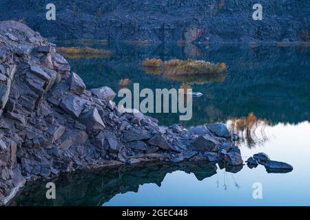 Piccolo lago circondato da rifiuti di pietra provenienti da lavori minerari Foto Stock