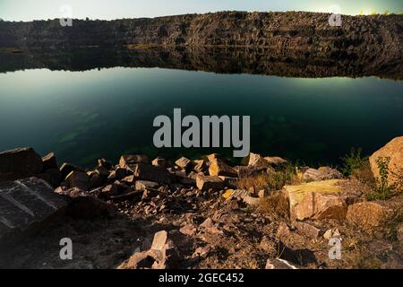 Piccolo lago circondato da rifiuti di pietra provenienti da lavori minerari Foto Stock