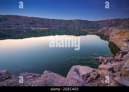 Piccolo lago circondato da rifiuti di pietra provenienti da lavori minerari Foto Stock