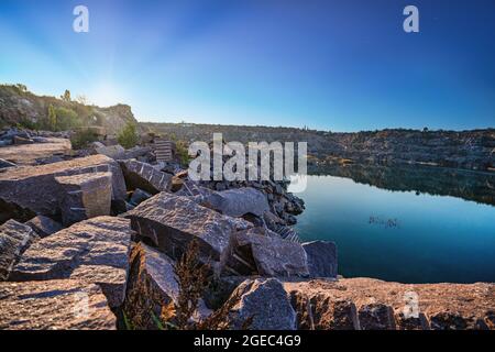 Piccolo lago circondato da rifiuti di pietra provenienti da lavori minerari Foto Stock