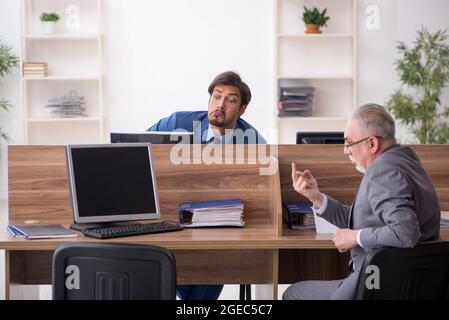 Due dipendenti di sesso maschile che lavorano sul posto di lavoro Foto Stock