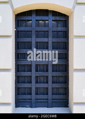 Una finestra ad arco con barre di ferro su un edificio in pietra Foto Stock