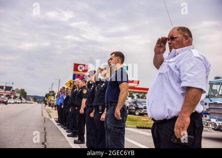 Bloomington, Stati Uniti. 18 agosto 2021. I vigili del fuoco rendono onore durante la processione funeraria del paramedico caduto Brandon Staley su W. Morgan Street a Spencer, Indiana.Staley morì per un attacco di cuore mentre lavorava come paramedico per Owen County EMS (Emergency Medical Services). Staley aveva appena risposto a un incidente stradale e si trovava in un'ambulanza con i sopravvissuti agli incidenti che li aiutavano durante il viaggio verso un ospedale quando egli stesso si ammalò. Credit: SOPA Images Limited/Alamy Live News Foto Stock