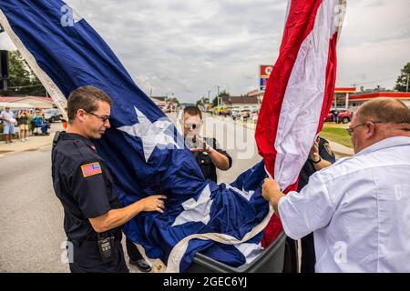 Bloomington, Stati Uniti. 18 agosto 2021. I vigili del fuoco alzano una bandiera americana per la processione funeraria del paramedico caduto Brandon Staley su W. Morgan Street a Spencer, Indiana.Staley è morto da un attacco di cuore mentre lavorava come paramedico per Owen County EMS (Emergency Medical Services). Staley aveva appena risposto a un incidente stradale e si trovava in un'ambulanza con i sopravvissuti agli incidenti che li aiutavano durante il viaggio verso un ospedale quando egli stesso si ammalò. Credit: SOPA Images Limited/Alamy Live News Foto Stock