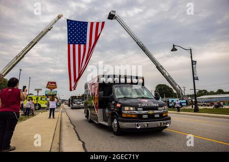 Bloomington, Stati Uniti. 18 agosto 2021. Una bandiera americana è volata su W. Morgan Street durante una processione funeraria per il caduto paramedico Brandon Staley a Spencer, Indiana.Staley è morto da un attacco di cuore mentre lavorava come paramedico per Owen County EMS (Emergency Medical Services). Staley aveva appena risposto a un incidente stradale e si trovava in un'ambulanza con i sopravvissuti agli incidenti che li aiutavano durante il viaggio verso un ospedale quando egli stesso si ammalò. (Foto di Jeremy Hogan/SOPA Images/Sipa USA) Credit: Sipa USA/Alamy Live News Foto Stock