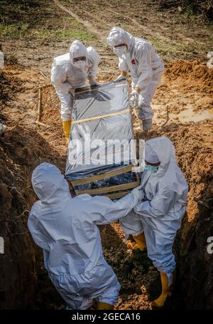 Kendari, Indonesia. 18 agosto 2021. (NOTA PER I REDATTORI: Immagine della morte) gli operatori sanitari vestiti con tute protettive portano una bara di una vittima di Covid-19 per la sepoltura. Il processo funerario per i pazienti di Covid-19 con protocolli sanitari è effettuato da operatori sanitari ospedalieri a Kendari. Sebbene il numero di pazienti trattati con COVID-19 sia in diminuzione, il tasso di mortalità è costante ogni giorno. (Foto di Andry Denisah/SOPA Images/Sipa USA) Credit: Sipa USA/Alamy Live News Foto Stock