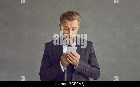 Un uomo d'affari sorpreso ha ricevuto notizie scioccate sul ritratto dello studio del telefono mobile Foto Stock