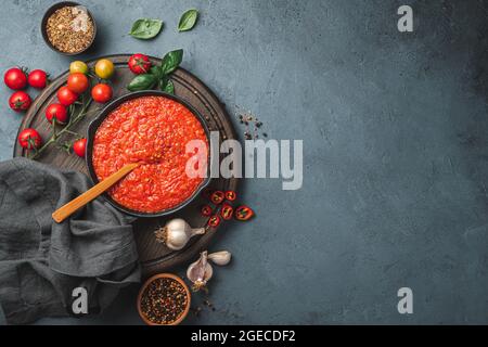 Salsa di marinara italiana di base e ingredienti freschi su sfondo scuro. Condimento per pasta. Vista dall'alto, orizzontale. Foto Stock