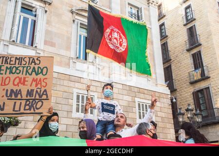 Barcellona, Catalogna, Spagna. 18 agosto 2021. Un bambino è visto con una bandiera afghana accanto ai manifestanti dietro una bandiera afghana.circa cinquecento persone hanno manifestato a Barcellona in solidarietà con le ragazze e le donne afghane e in difesa dei loro diritti sotto lo slogan ''Afghanistan: Per una vita con dignità e libertà' (immagine di credito: © Thiago Prudencio/DAX tramite CAVO ZUMA Press) Foto Stock