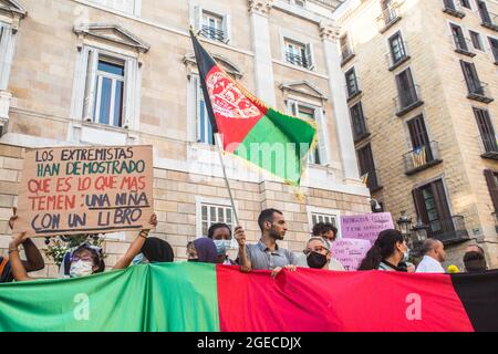 Barcellona, Catalogna, Spagna. 18 agosto 2021. Il manifestante è visto con una bandiera afghana accanto ai manifestanti dietro una bandiera afghana e un segno che dice, gli estremisti hanno dimostrato ciò che temono di più: Una ragazza con un libro.circa cinquecento persone hanno dimostrato a Barcellona in solidarietà con le ragazze e le donne dell'Afghanistan e in difesa dei loro diritti sotto lo slogan ''Afghanistan: Per una vita con dignità e libertà' (Credit Image: © Thiago Prudencio/DAX via ZUMA Press Wire) Foto Stock