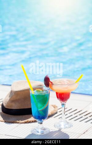 Due colorati bicchieri da cocktail e cappello al bordo della piscina. Con spazio per la copia Foto Stock