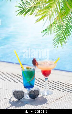 Due colorati bicchieri da cocktail ai bordi della piscina. Con spazio per la copia Foto Stock