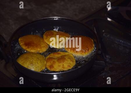 Frittura indiano famoso cibo chapati su stufa a gas GPL, olio bollente in padella con sfondo scuro Foto Stock