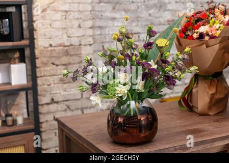 Bouquet di fiori in un autentico vaso elegante. Set di fiori e germogli di eustoma viola e bianco Foto Stock