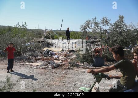 Balashun, Siria. 19 agosto 2021. La gente cerca i superstiti sotto le macerie di una casa dopo un missile che lo ha preso di mira nella città di Balashun nella regione di Jabal al-Zawiya (Monte Zawiya). Credit: ANAS Alkharboutli/dpa/Alamy Live News Foto Stock