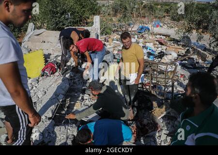 Balashun, Siria. 19 agosto 2021. La gente cerca i superstiti sotto le macerie di una casa dopo un missile che lo ha preso di mira nella città di Balashun nella regione di Jabal al-Zawiya (Monte Zawiya). Credit: ANAS Alkharboutli/dpa/Alamy Live News Foto Stock