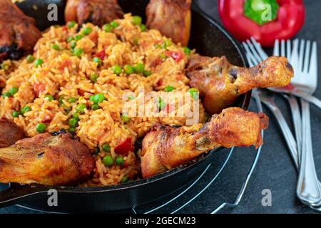 Bastoncini di pollo arrosto con riso serbo djuvec servito in una padella di ghisa su sfondo scuro del tavolo Foto Stock