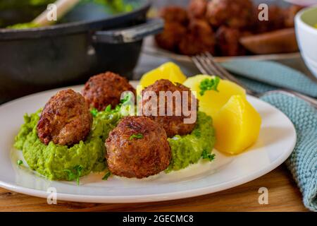 Polpette fritte con purea di piselli e patate su un piatto con sfondo da tavolo da cucina. Foto Stock