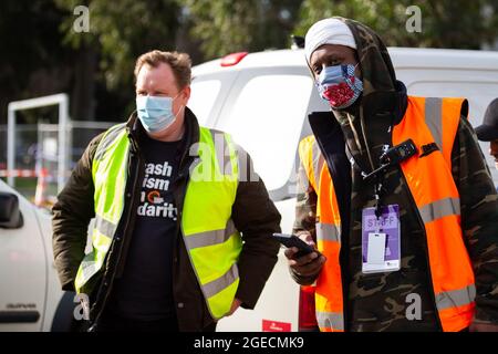 Melbourne, Australia, 10 luglio 2020. Il segretario del consiglio della Victorian Trades Hall, Luke Hilakari (a sinistra) guarda con un funzionario (a destra) mentre un camion pieno di carne arriva ad Alfred Street durante il COVID-19 il 10 luglio 2020 a Melbourne, Australia. L'ex leader del lavoro federale Bill accorciare, insieme agli alleati stretti della Trades Hall aiutano a consegnare la carne di Halal, fornita da Macca Halal Foods alle torri della commissione immobiliare chiuse a chiave a seguito di un'epidemia di coronavirus rilevata all'interno del complesso. Il signor abbreviato è riuscito a utilizzare il suo alto profilo per garantire che il cibo non sia stato allontanato dalla polizia in modo che si trasformasse in cibo Foto Stock